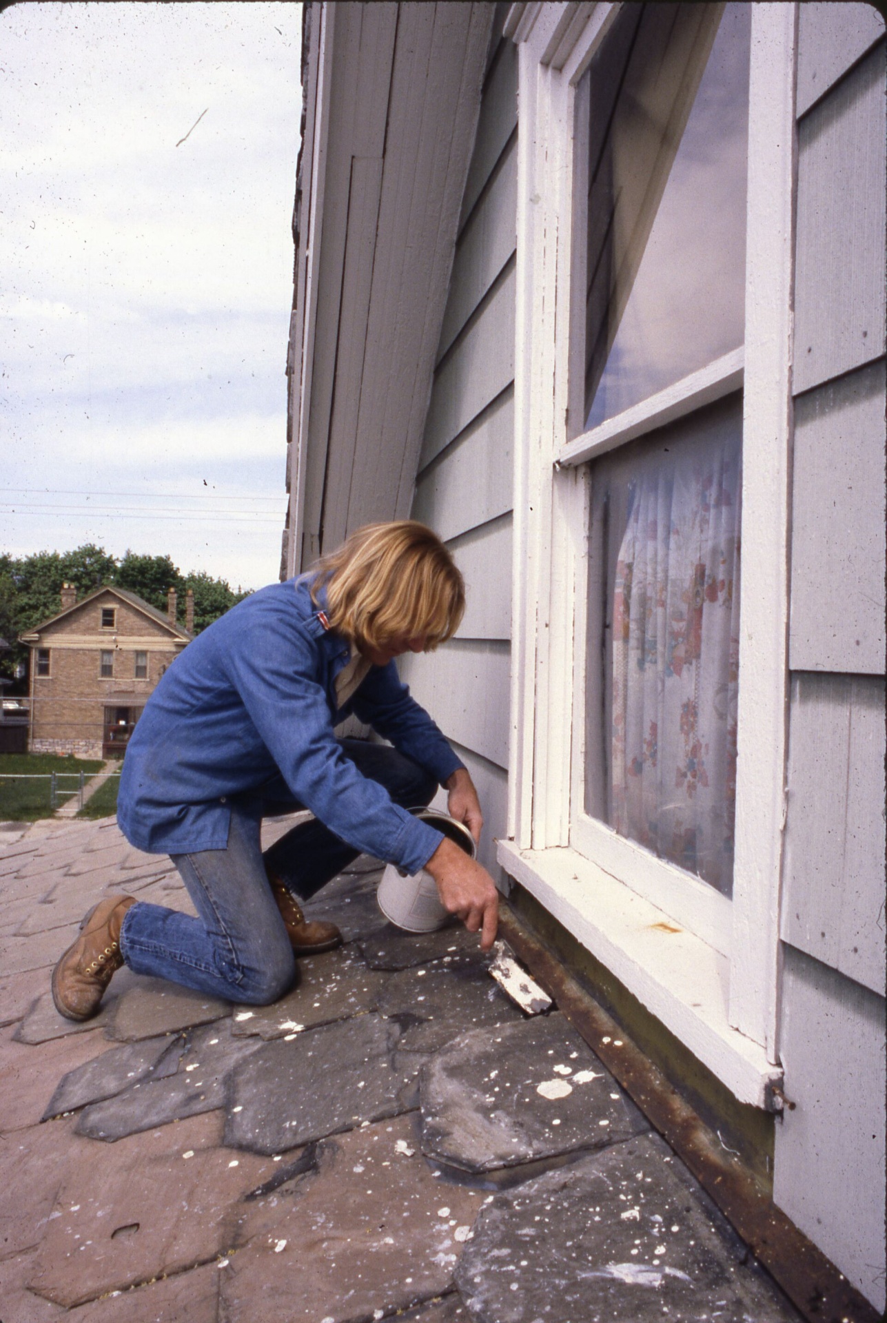 Inspector on a roof examining shingles up close in KC Northland neighborhood
